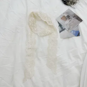 Gedetailleerde weergave van een crème bloemen kant lint sjaal voor haar of taille