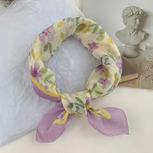 Primer plano del elegante estampado floral anudado en un pañuelo cuadrado morado y amarillo