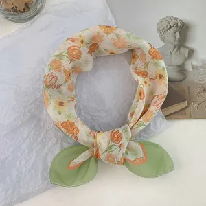 Elegante bufanda de seda con motivos florales naranjas y bordes anudados verde claro
