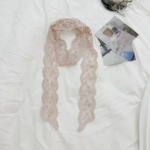 Gedetailleerd bovenaanzicht van een delicate vintage bloemen kant lint sjaal op wit linnen
