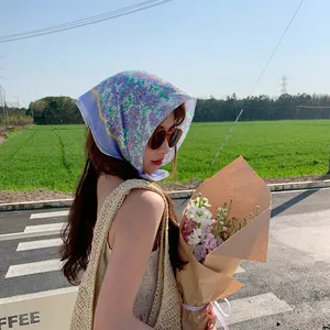 Lifestyle-Aufnahme einer Frau mit einem floralen Baumwollkopftuch und einem Blumenstrauß im Freien