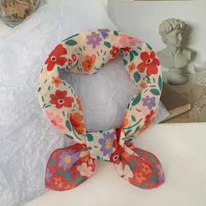 Primer plano de un pañuelo cuadrado floral con motivos rojos y morados sobre papel
