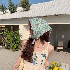 Frau mit minzgrünem geblümtem Baumwollkopftuch in einer sonnigen Urlaubslandschaft