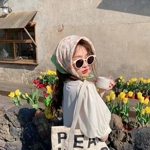 Stilvolle Frau mit einem Alice Garden Blumen-Baumwoll-Kopftuch für den Sonnenschutz