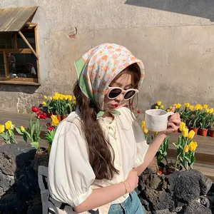 Asiatisches Model trägt ein florales Baumwoll-Kopftuch zum Sonnenschutz in einem Garten