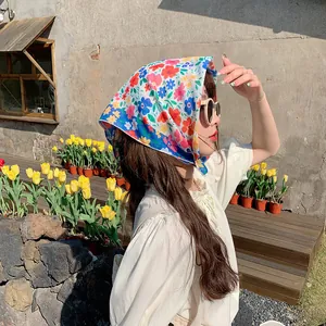 Modelo asiática con pañuelo bandana de algodón y lino con flores en un jardín soleado
