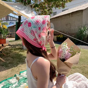 Außenaufnahme eines floralen Baumwollkopftuchs, getragen von einem Modell im Garten.