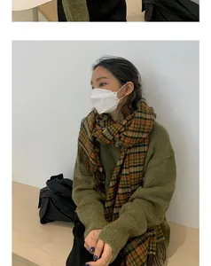 Gros plan d'une femme portant une écharpe à carreaux orange et un pull vert confortable