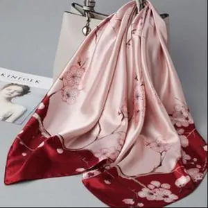 Detail of pink floral satin scarf with elegant plum blossom print and silky texture.