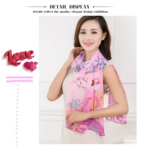 Detailed shot of an elegant pink chiffon scarf featuring a floral and bird print on a model