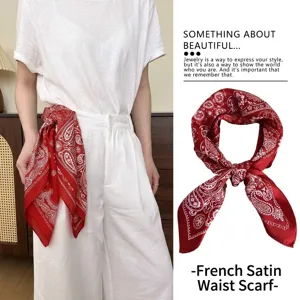 Detail showing a red retro paisley satin scarf used as a stylish waist belt on white trousers