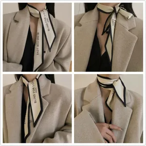 Close-up of narrow silk scarf with 'Blind for Love' text worn with a beige blazer