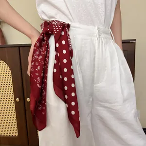 Red paisley and polka dot silk scarf tied as a decorative belt on white trousers