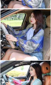 Asian woman wearing printed chiffon sun protection sleeves while driving, showing ruffled cuffs.