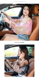 Model wearing pink and black paisley chiffon sun protection shawl in car interior setting