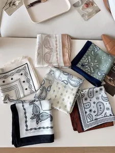 A collection of assorted vintage paisley silk square scarves on a stylish white desk