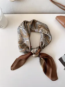 Detailed view of a knotted retro paisley silk scarf in brown and cream shades on white surface.