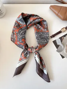 Detailed macro view of an elegant orange and grey paisley pattern silk scarf for women
