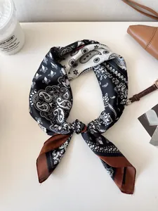 Elegant paisley pattern silk scarf with brown borders in a stylish flat lay arrangement.