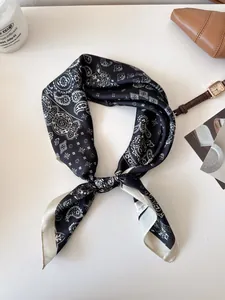Detailed view of vintage black and white paisley pattern silk square scarf on desk