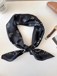 Detail shot of a black paisley silk scarf knotted in a vintage style.