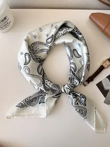 Detail view of a retro white silk scarf with an elegant black paisley pattern knot