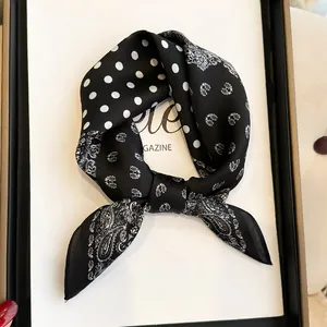 Detailed view of black and white silk neck scarf with paisley and polka dot pattern