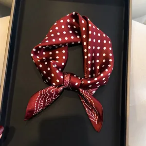 Close-up of elegant burgundy silk scarf with white polka dots and paisley patterns.