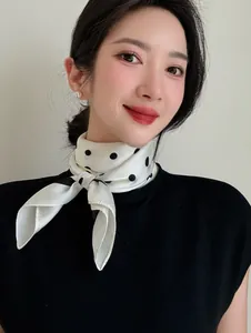 Close-up detail of an elegant white silk scarf with black polka dots on a neck