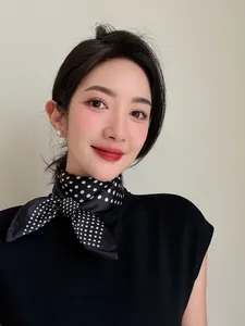 Elegant black polka dot silk neck scarf worn by a model against a neutral background