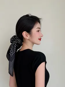 Elegant black and white polka dot silk scarf styled as a hair accessory for women.