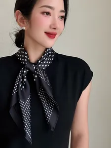 Close-up of elegant black and white polka dot silk small square scarf styled as a neckerchief