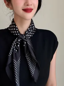 Elegant black silk scarf featuring white polka dots, styled as a chic neck tie accessory.