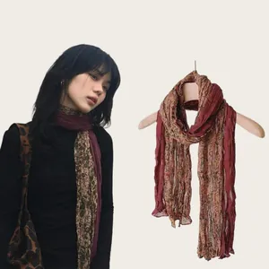 Retro floral scarf detail shown on model and wooden hanger for stylish neck accessory.