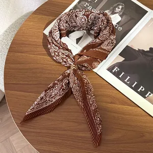 Detailed view of a brown pleated paisley silk scarf elegantly tied with a gold ring