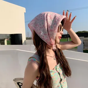 Woman wearing pink floral linen headscarf in an outdoor sunny setting