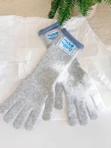 Detalle de guantes de punto de invierno grises con borde azul y parche de logo elegante