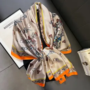 Detailansicht eines eleganten Seidenschals mit Schmetterlingen und orangefarbenem Rand.