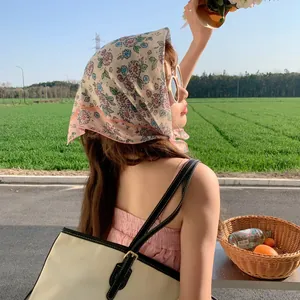 Young woman wearing a floral cotton-linen headscarf in a sunny outdoor field setting.