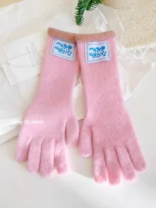 Vista detallada de guantes largos de punto rosas con una etiqueta azul estética