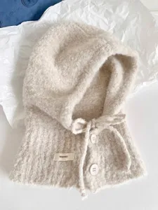 Nahaufnahme eines beigen Woll-Balaclava-Schals mit Knopf- und Schleifendetail
