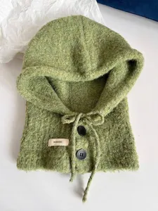 Detailansicht einer gestrickten salbeigrünen Sturmhaube mit schwarzen Knöpfen und Kordelzug.