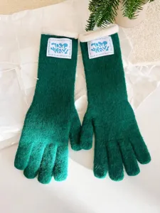 Primer plano de guantes de punto verdes para invierno con puños de forro polar blanco
