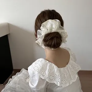 Rückansicht einer Frau mit einem großen cremefarbenen Organza Haargummi im Dutt
