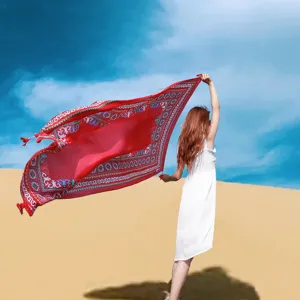 Detailed view of a vibrant red ethnic shawl flowing in the desert breeze under blue sky.