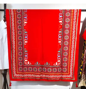 Detailed view of ethnic red shawl with vibrant turquoise patterns and tassels