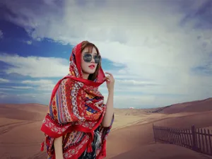 Detail view of a model in a red ethnic shawl posing in a scenic desert landscape setting.