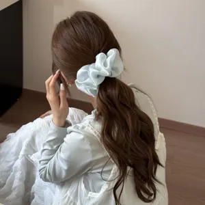 Elegant light blue mesh scrunchie shown in a stylish low ponytail hair accessory detail