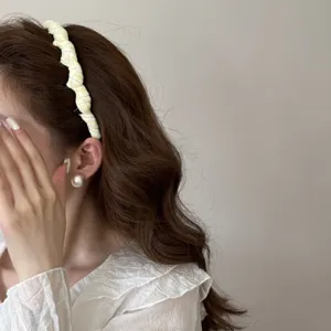 Detailed side view of a stylish checkered fabric headband creating a high-skull hair look.