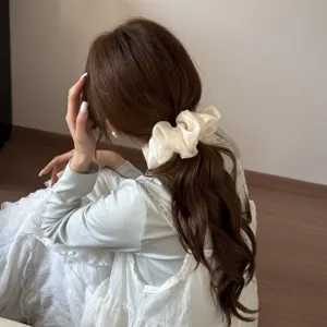 Close-up view of elegant cream-colored mesh scrunchie worn on a stylish low ponytail